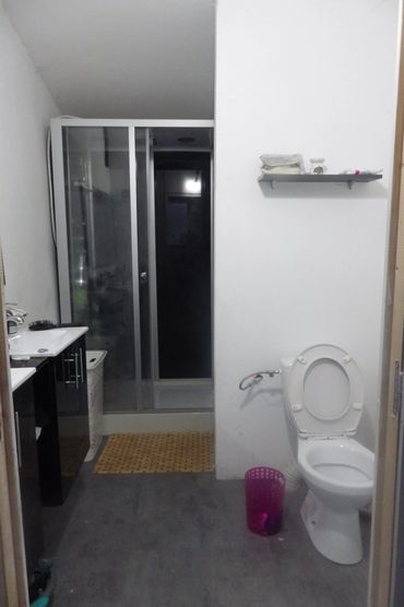 Salle de bain simple avec douche et toilettes.