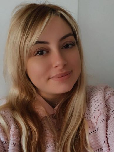 Young woman with long blonde hair smiling gently at the camera.