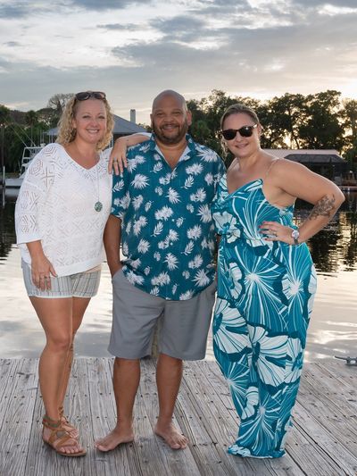 Three people on a pier at sunset