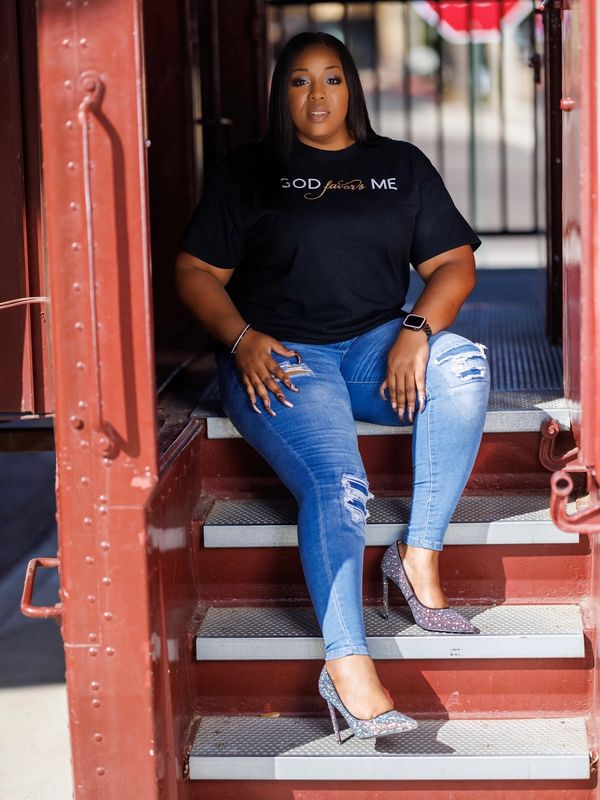 Woman sitting confidently on red metal stairs in jeans and glittery heels.