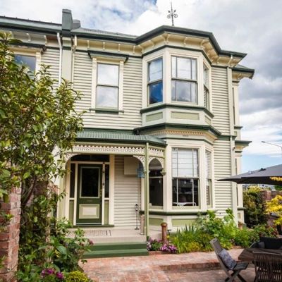Victorian-style two-story house with green trim and a small garden.