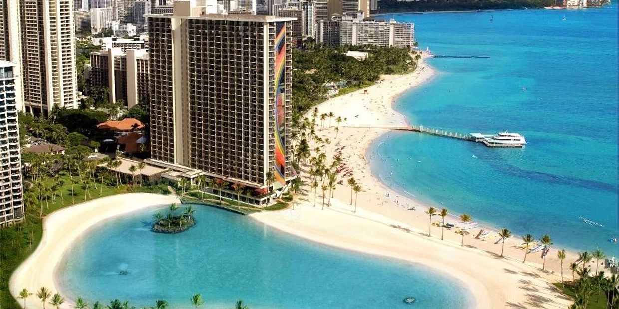 Beachfront hotel with a lagoon and city skyline.
