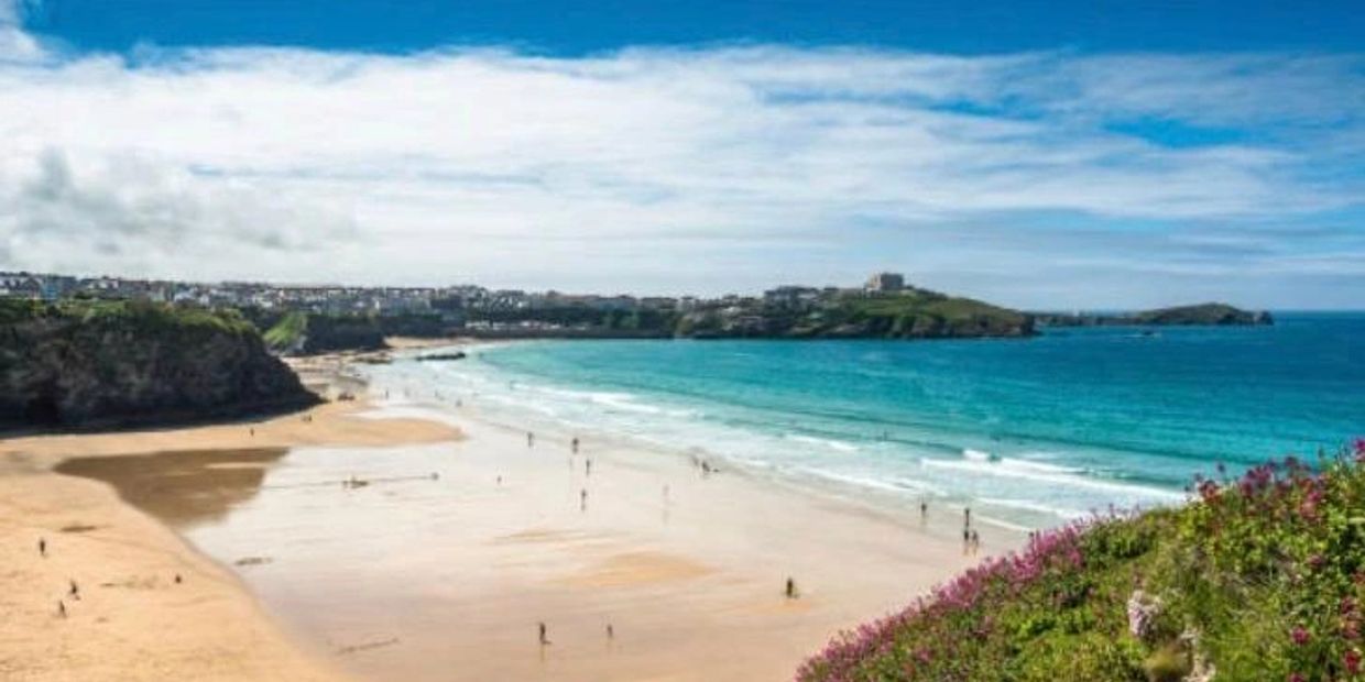 Sandy beach with blue ocean and people walking.