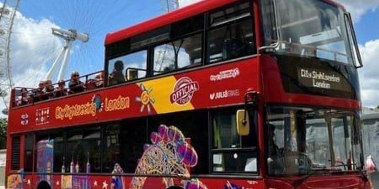 Red double-decker bus with tourists in London.