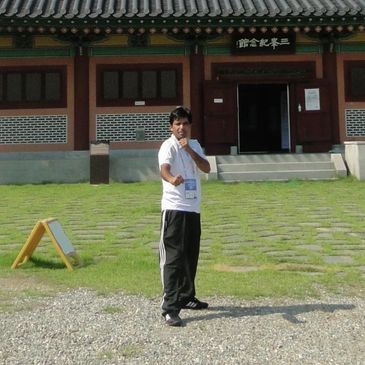 People standing in front of a traditional Korean-style building on a sunny day.