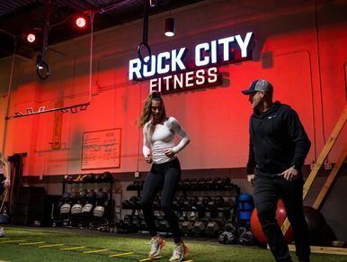 Personal trainer and female client using agility ladder for sports performance training.