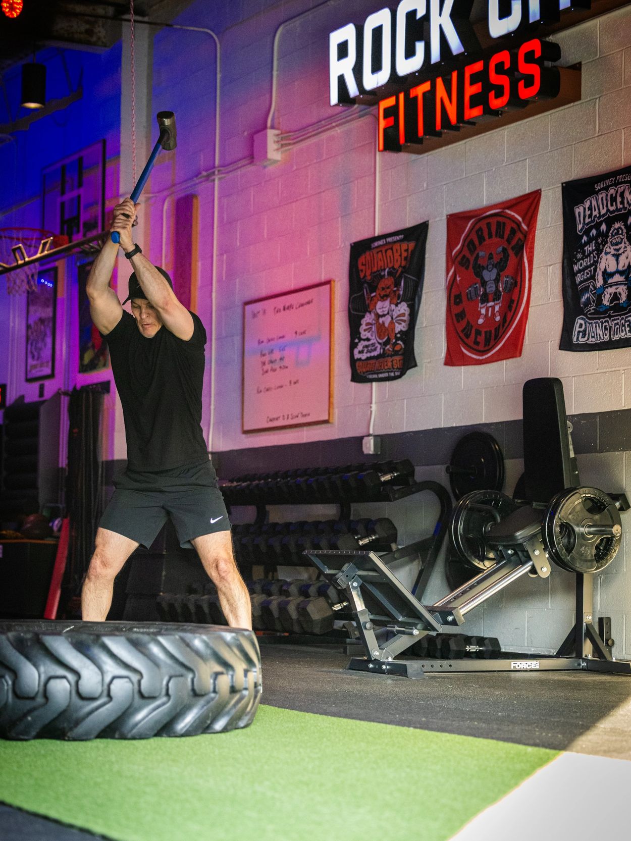 Man swinging sledgehammer during intense gym workout.