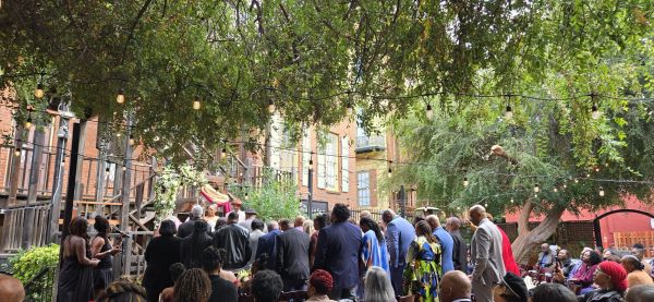 People gathered outdoors under string lights near buildings and trees.