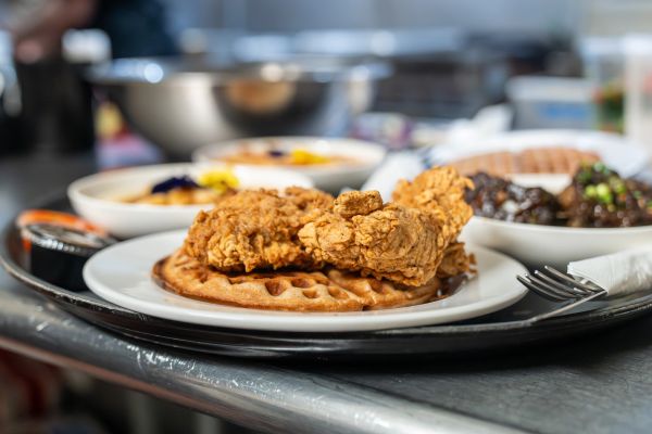 Crispy fried chicken served on a waffle on a white plate.