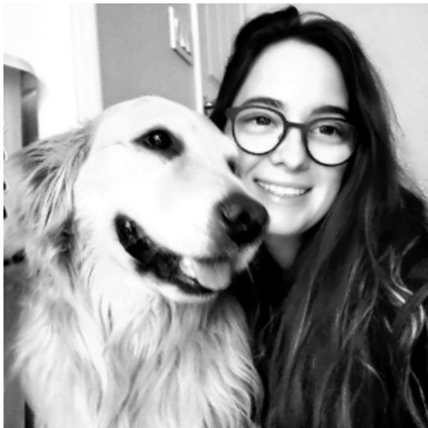 Happy young woman with glasses posing with her smiling golden retriever.