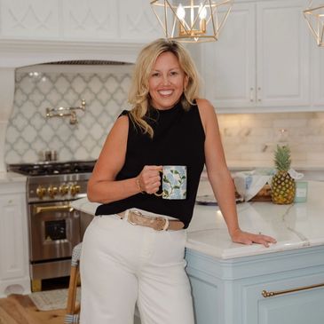 Woman smiling in modern kitchen holding a mug.