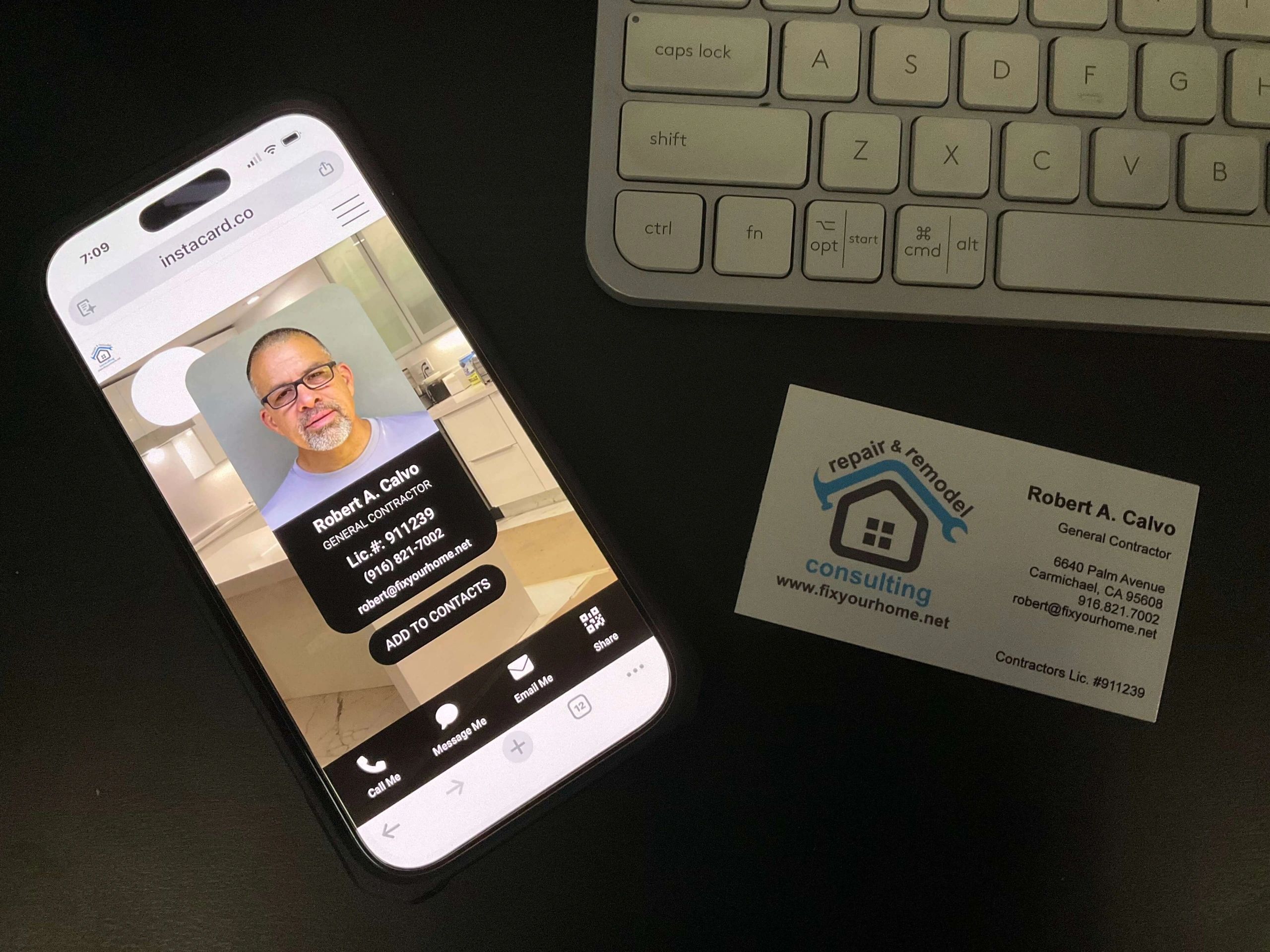 A picture of a cellphone, business card and a keyboard.