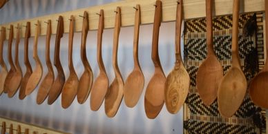 Row of wooden spoons hanging on a wooden rack.