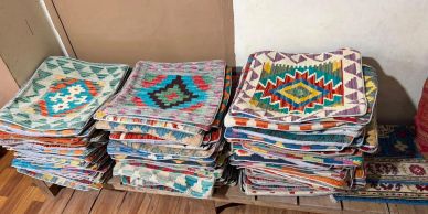 Stacks of folded colorful patterned rugs.