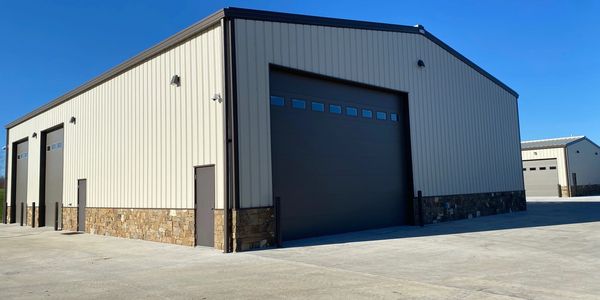 Modern industrial building with large garage doors under a clear blue sky.