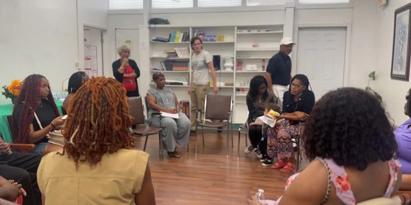 A diverse group of people sitting in a circle in a community room.