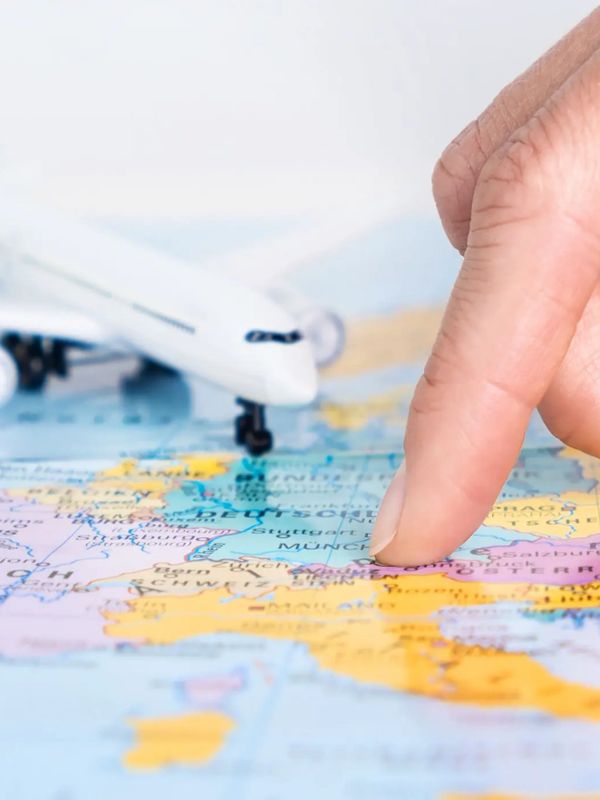A hand points to a location on a map with a toy airplane nearby.