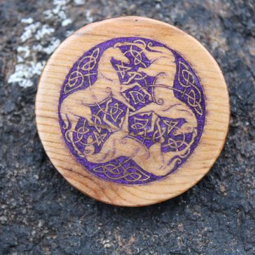 Wooden token with a purple Celtic triple horse knot design.