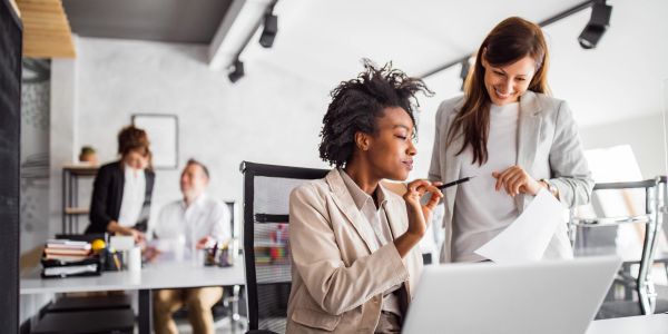 Two women collaborating on work in a modern office setting.