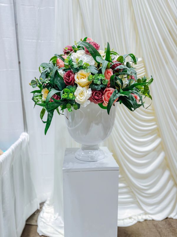 White vase with colorful flowers on a pedestal.