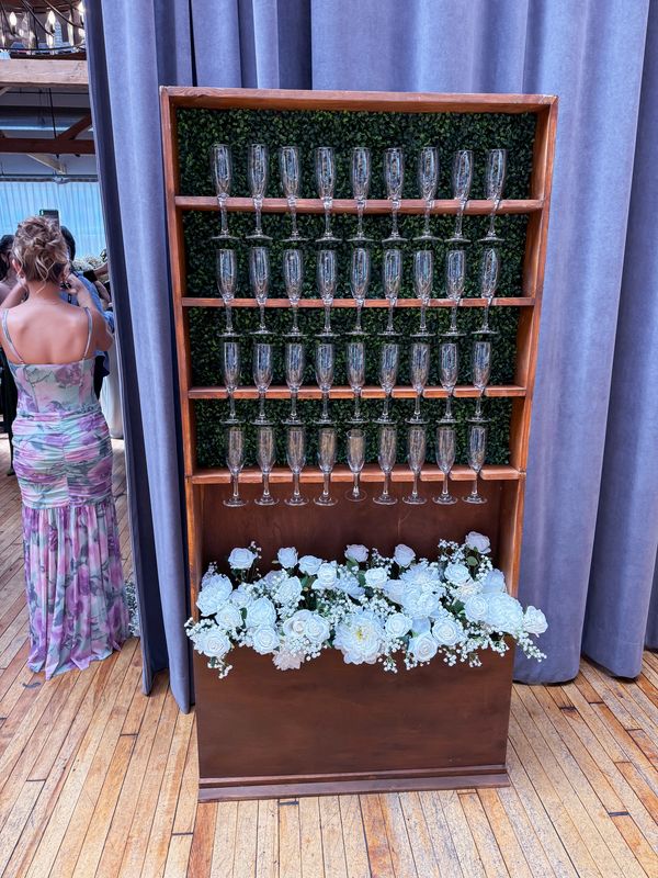 Shelves of empty glasses with floral decoration below.