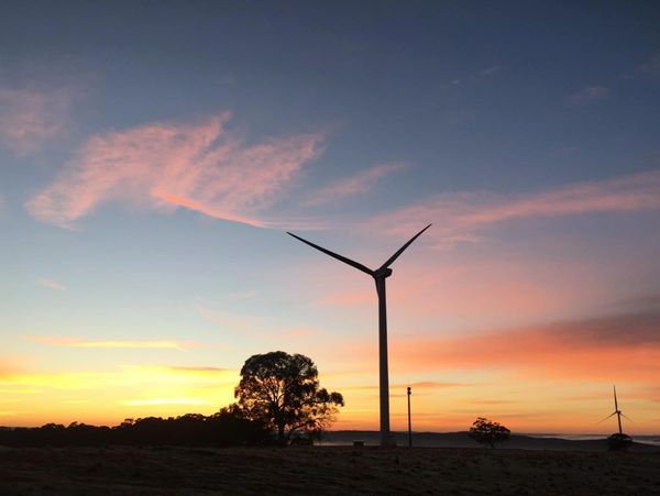Wind turbines stand tall against a colorful sunset sky.
