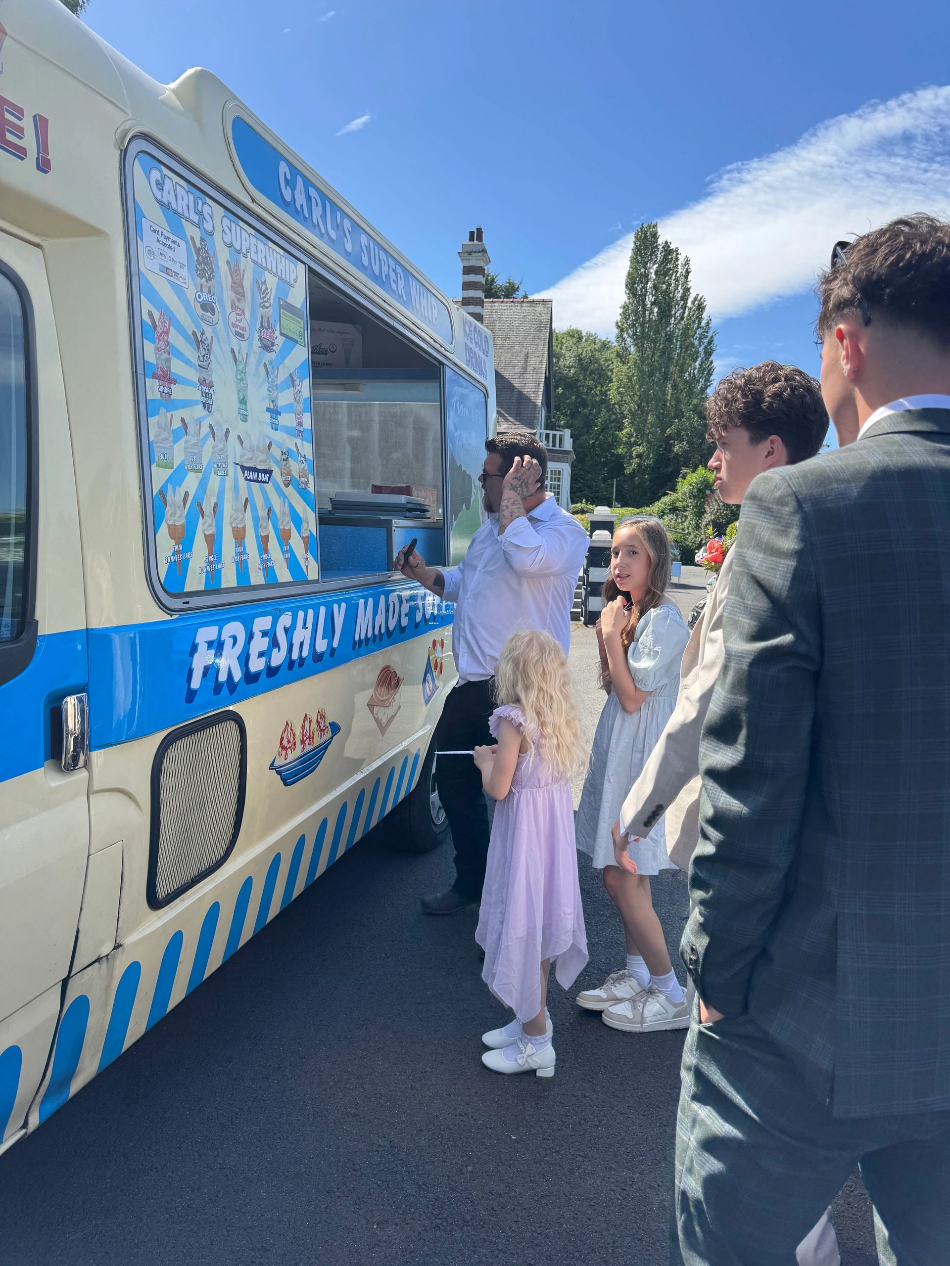 People waiting at an ice cream truck on a sunny day.