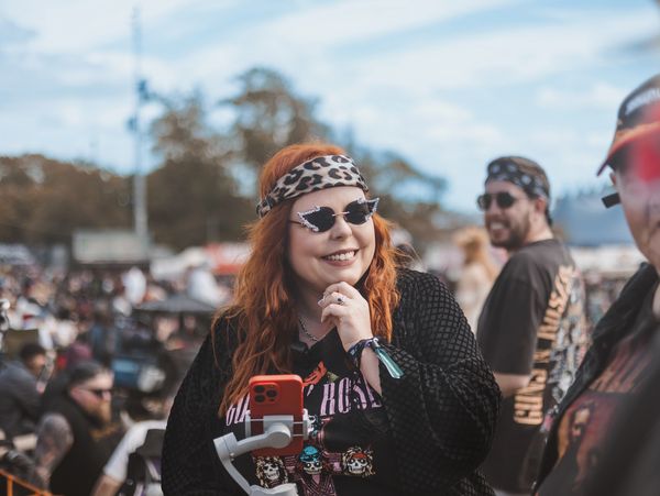 Smiling woman at outdoor event with sunglasses and leopard headband.