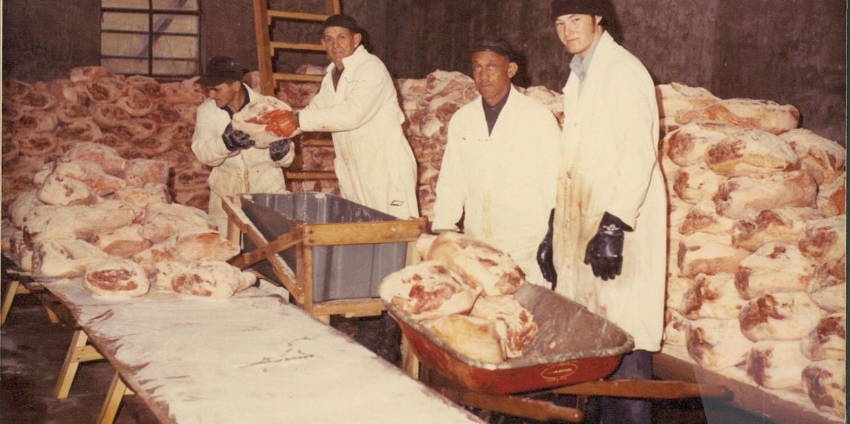 workers surrounded by raw hams