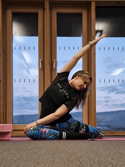 A woman practicing yoga indoors in a side stretch pose.