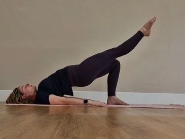 Woman performing a single-leg bridge exercise on a yoga mat.