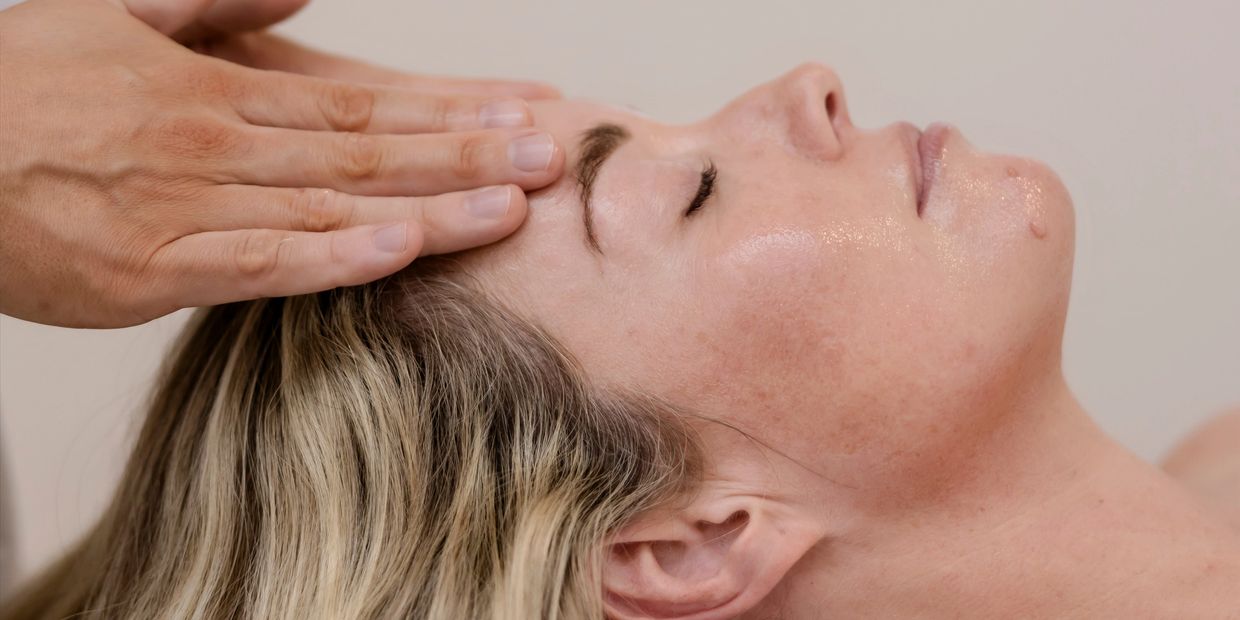 Person receiving a forehead massage with closed eyes.