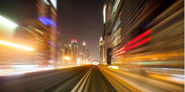 Visão noturna de um túnel urbano com luzes em movimento.
