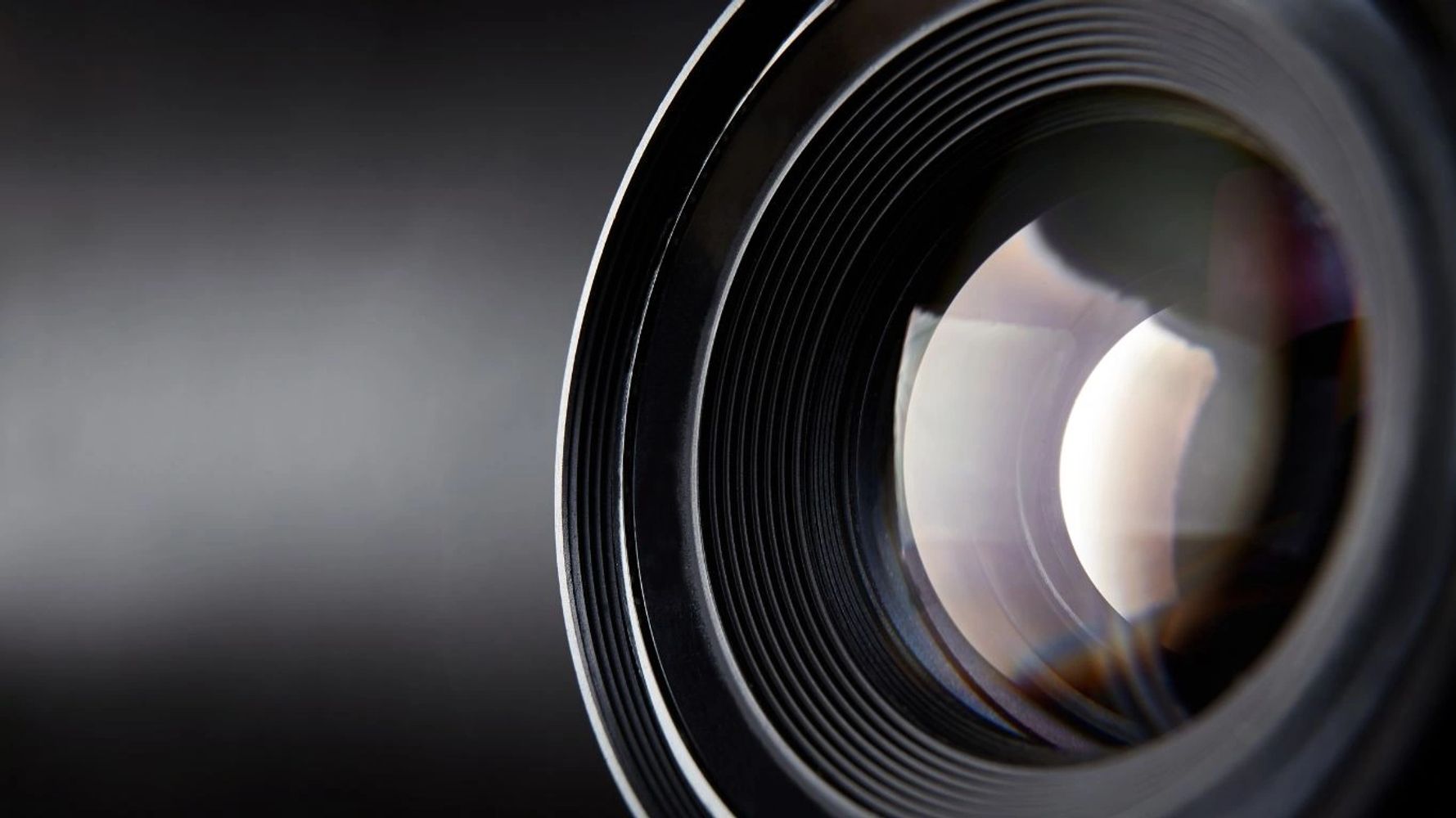 Close-up of a camera lens with light reflections.