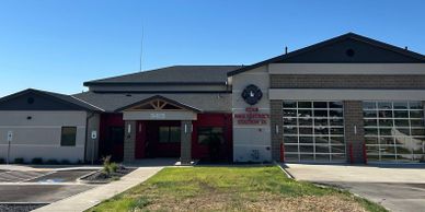 Modern fire station building with garage doors and clear blue sky.