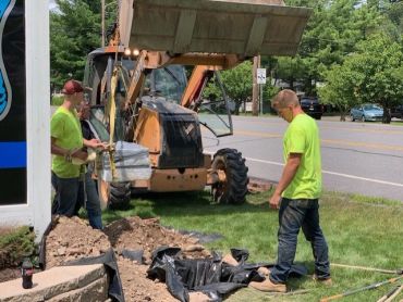 Two workers operate machinery and prepare dirt for landscaping or construction.