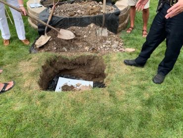 People digging a hole in the grass with shovels.