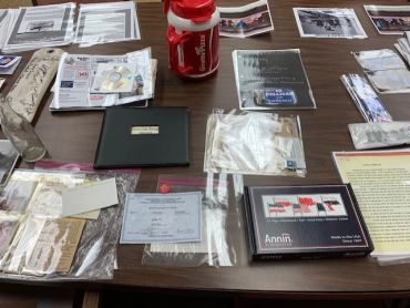 A table displaying historical documents, photos, and memorabilia organized in plastic sleeves.