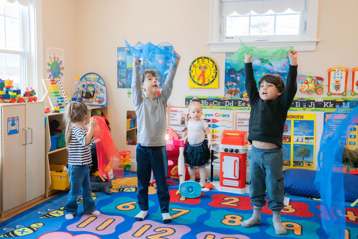 Children playing with colorful scarves in a lively classroom.