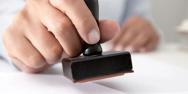 Close-up of a notary public applying an official stamp to a legal document. Mobile notary services.
