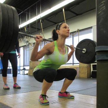 Woman performing weighted squats in a gym.