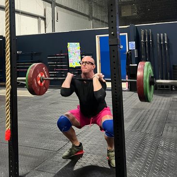 Man doing heavy weightlifting squat at gym.