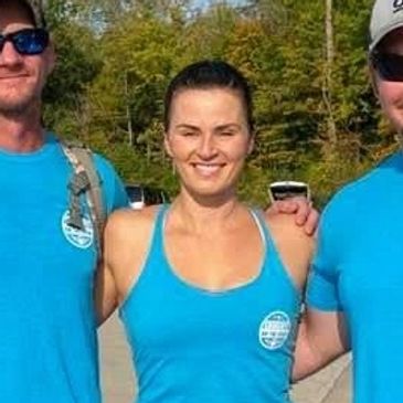 Three people in blue shirts posing outdoors.