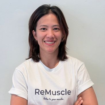 Smiling woman with crossed arms wearing a ReMuscle t-shirt.