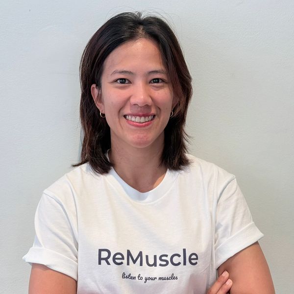 Smiling woman with crossed arms wearing a ReMuscle t-shirt.