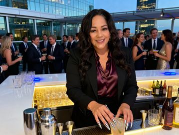 Woman making a cocktail at a bar during a formal event.