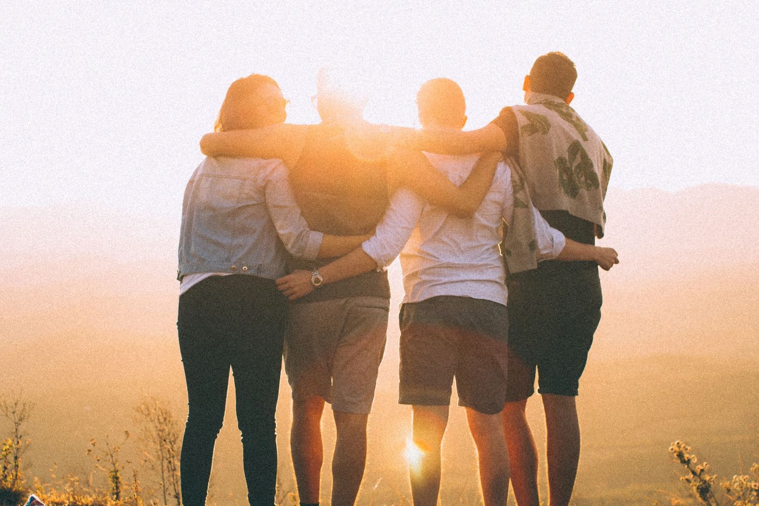 Greeting picture of four people arm in arm to set theme of website.