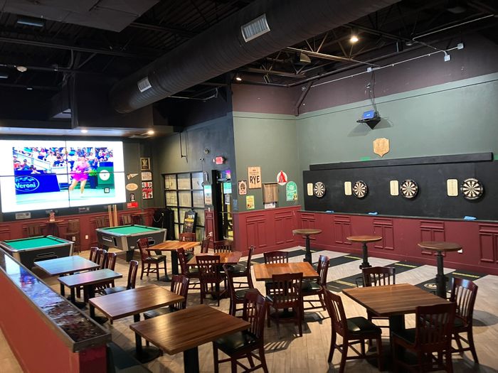 Indoor game room with pool tables, dart boards, and seating area.