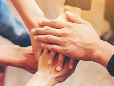 Multiple hands stacked together symbolizing unity and support.