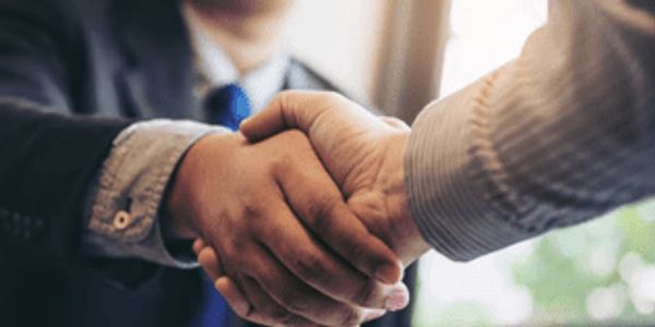Two people shaking hands in a professional setting.